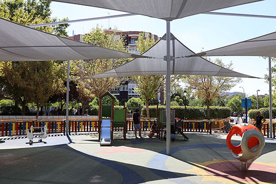 A shaded playground with a grey shade structure installation at the top. 